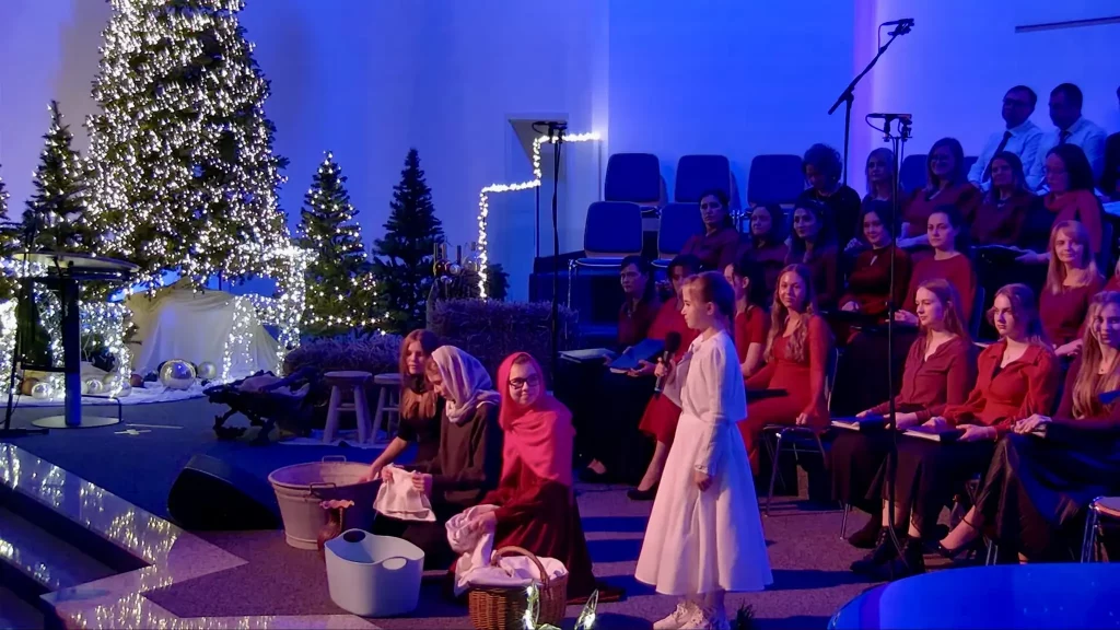 Ein Chor der christlichen Gemeinde in Niedernberg, davor sitzen Kinder beim Anspiel von Jesu Geburt